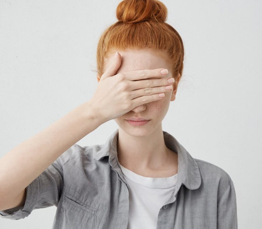 A woman with her hand covering her eyes.